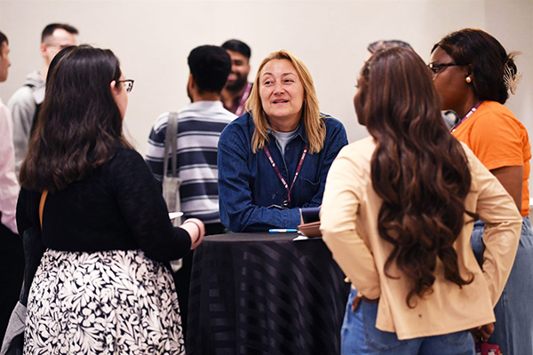 An SDSS attendee in conversation with a group of colleagues